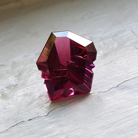 Fancy shape custom cut rhodolite garnet.  This striking fantasy cut garnet is deep raspberry red in color and has intense flashes of red, plum, purple and pink.  This untreated rhodolite is custom cut and one-of-a-kind